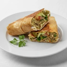 Vegan grilled falafel wrap with hummus, tahini, vegetables, caramelised onion, and pomegranate molasses.